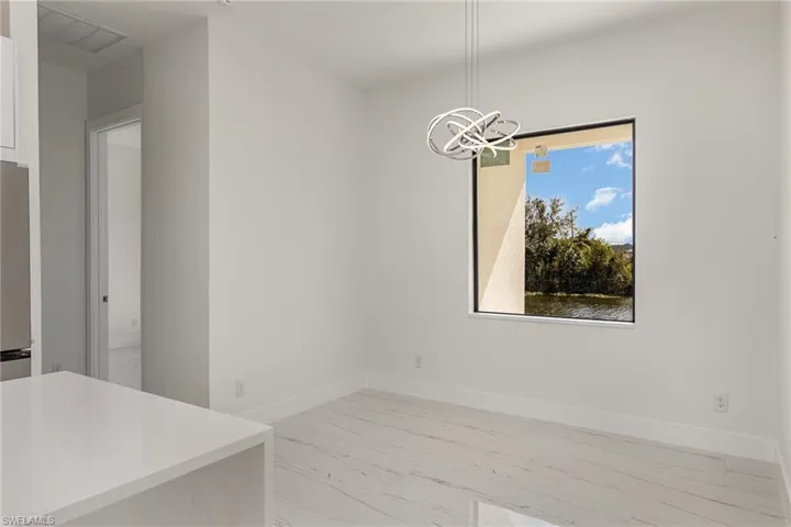 Unfurnished dining area with light marble finish flooring, a chandelier, and baseboards