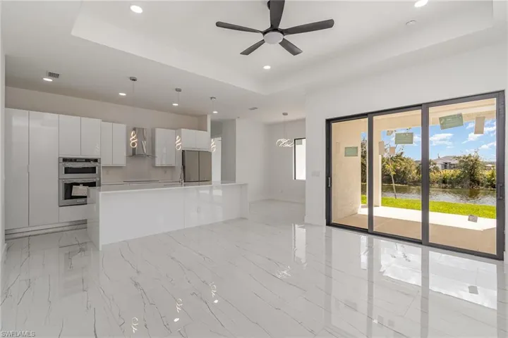 Kitchen with modern cabinets, a raised ceiling, appliances with stainless steel finishes, recessed lighting, and wall chimney exhaust hood