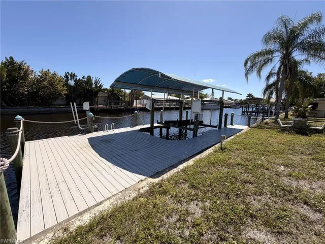Dock featuring a water view, boat lift, and a lawn
