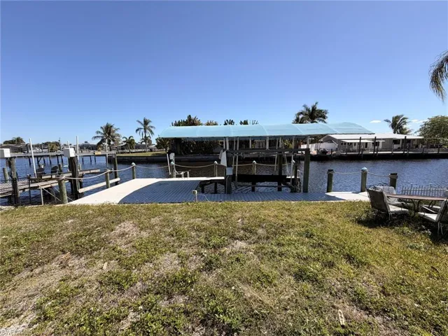Dock with boat lift, a yard, and a water view