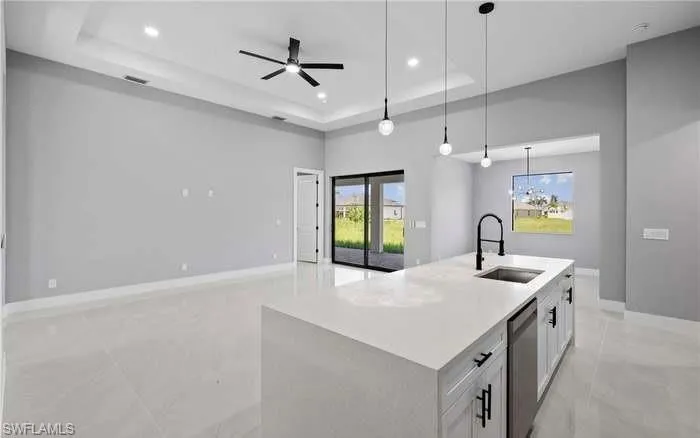Kitchen featuring white cabinets, an island with sink, dishwasher, pendant lighting, and sink