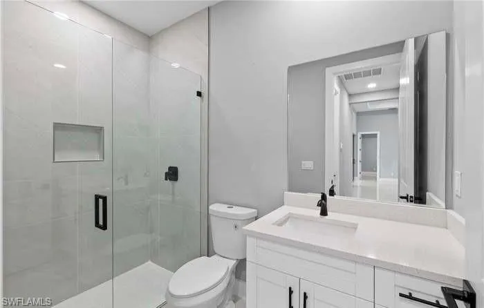 Bathroom with toilet, a shower with shower door, and vanity