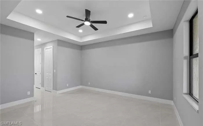 Empty room featuring a tray ceiling and ceiling fan