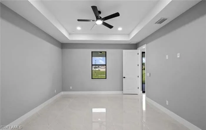 Empty room featuring a tray ceiling and ceiling fan
