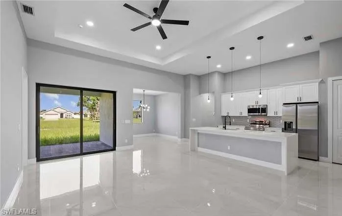 Kitchen featuring sink, a spacious island, white cabinetry, stainless steel appliances, and pendant lighting