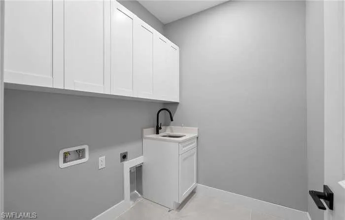 Laundry area with hookup for an electric dryer, cabinets, sink, and hookup for a washing machine