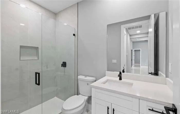 Bathroom featuring vanity, toilet, and an enclosed shower