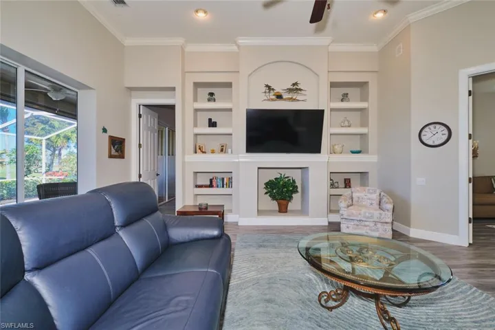 Living area with wood finished floors, a ceiling fan, built in features, ornamental molding, and recessed lighting