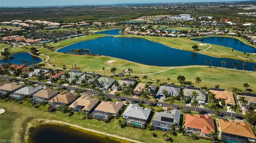 Aerial view of property and surrounding area featuring a large body of water, nearby suburban area, and a local golf course