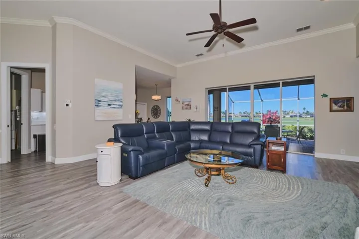 Living room featuring a ceiling fan, wood finished floors, and crown molding