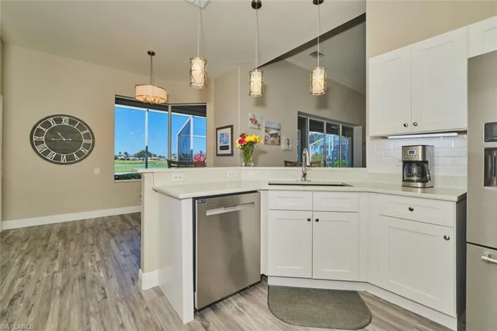 Kitchen featuring a peninsula, white cabinets, hanging light fixtures, stainless steel appliances, and tasteful backsplash