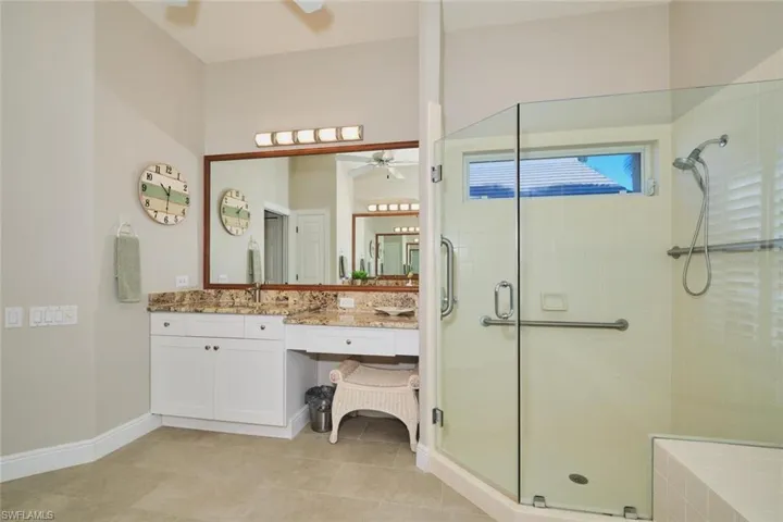 Full bath featuring vanity, a shower stall, light tile patterned floors, and a ceiling fan