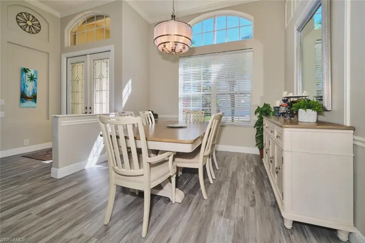 Dining space featuring crown molding, light wood-style floors, french doors, and hanging lights