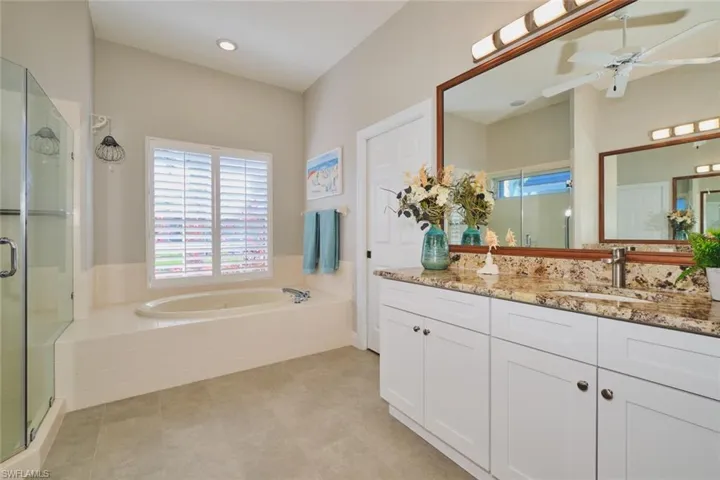 Bathroom with vanity, a stall shower, ceiling fan, a garden tub, and recessed lighting