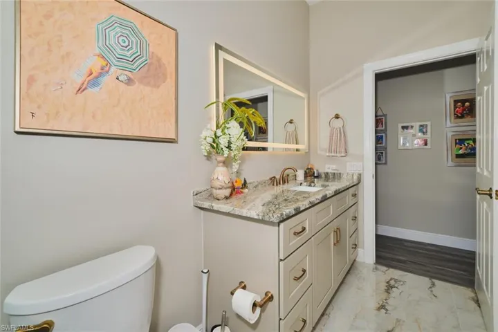 Half bath featuring vanity and light marble finish floors