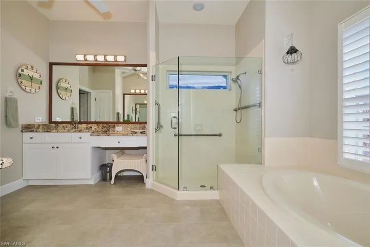 Full bath featuring vanity, a garden tub, a shower stall, light tile patterned floors, and ceiling fan