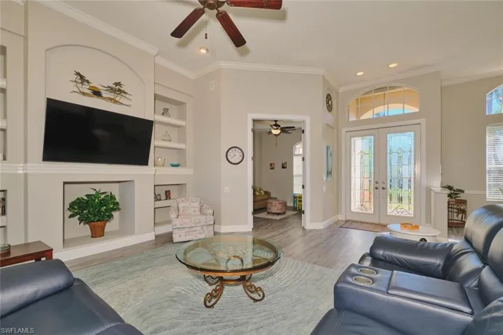 Living area featuring built in features, french doors, wood finished floors, ornamental molding, and ceiling fan