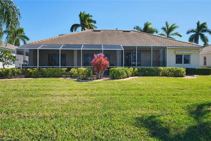 Rear view of house with a tiled roof, a yard, and a sunroom