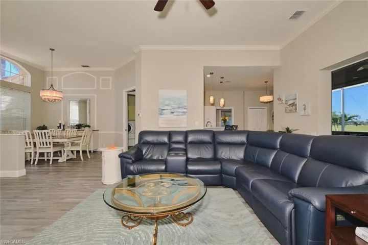 Living room featuring plenty of natural light, ornamental molding, light wood-type flooring, washer / dryer, and ceiling fan