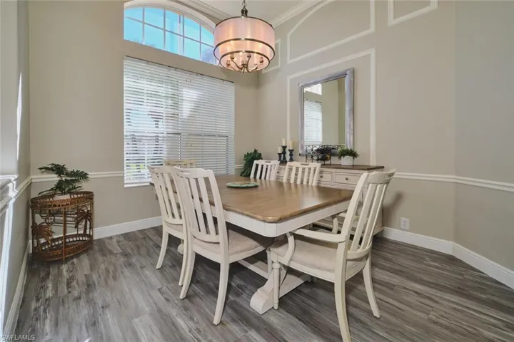 Dining space featuring dark wood-style flooring, suspended lighting, and a high ceiling