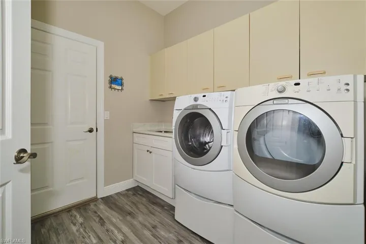 Laundry area with dark wood-style floors, separate washer and dryer, and cabinet space