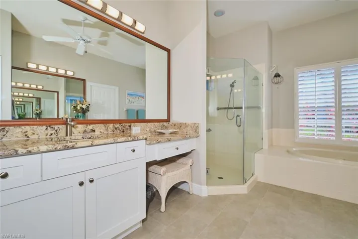 Bathroom with vanity, a stall shower, a ceiling fan, a garden tub, and light tile patterned floors