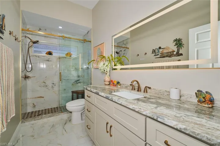Full bathroom with vanity, a marble finish shower, and light marble finish floors