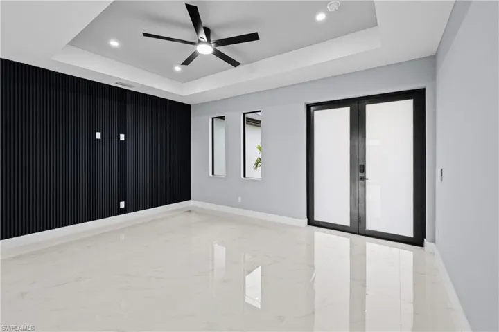Empty room featuring french doors, ceiling fan, and a tray ceiling