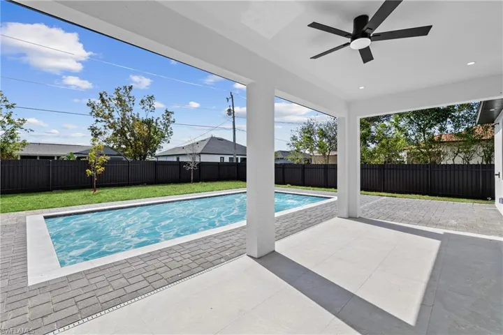 View of swimming pool with ceiling fan, a patio, and a lawn