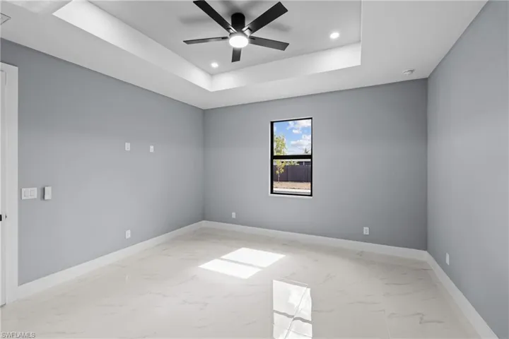 Unfurnished room featuring a tray ceiling and ceiling fan