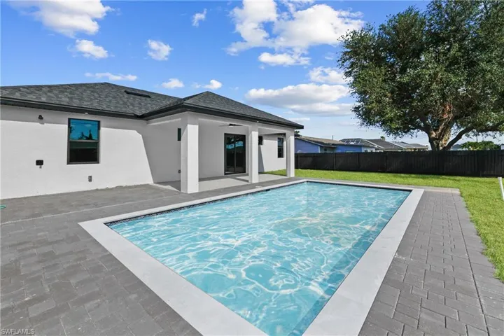 View of swimming pool with ceiling fan, a yard, and a patio area