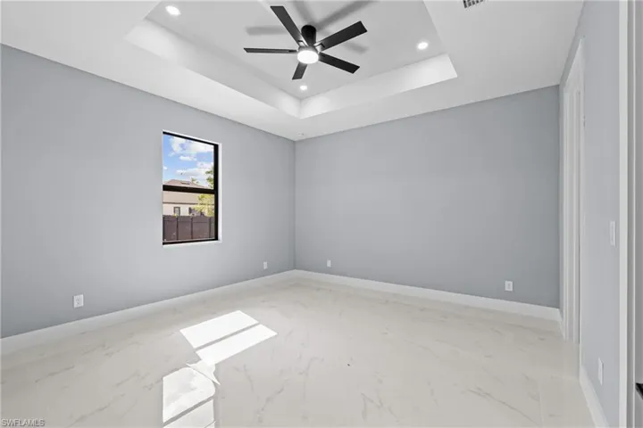 Spare room with ceiling fan and a tray ceiling