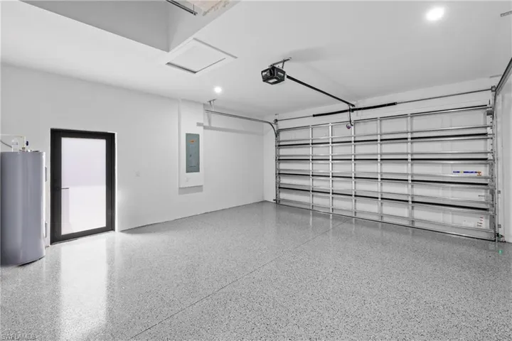 Garage with a garage door opener, electric panel, and water heater