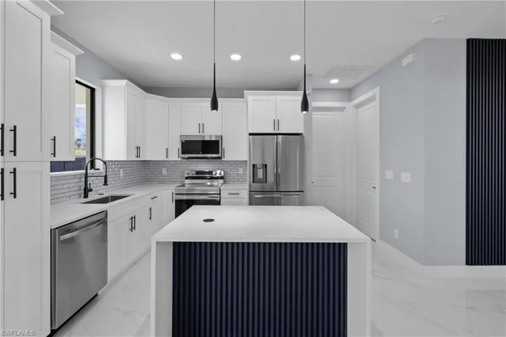 Kitchen with sink, white cabinetry, a center island, hanging light fixtures, and appliances with stainless steel finishes