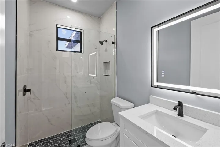 Bathroom featuring vanity, toilet, and a tile shower