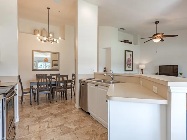 Kitchen featuring light countertops, a ceiling fan, suspended lighting, stainless steel appliances, and open floor plan