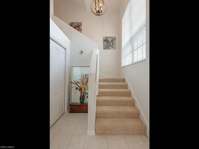 Staircase with tile patterned flooring, hanging lights, and a high ceiling