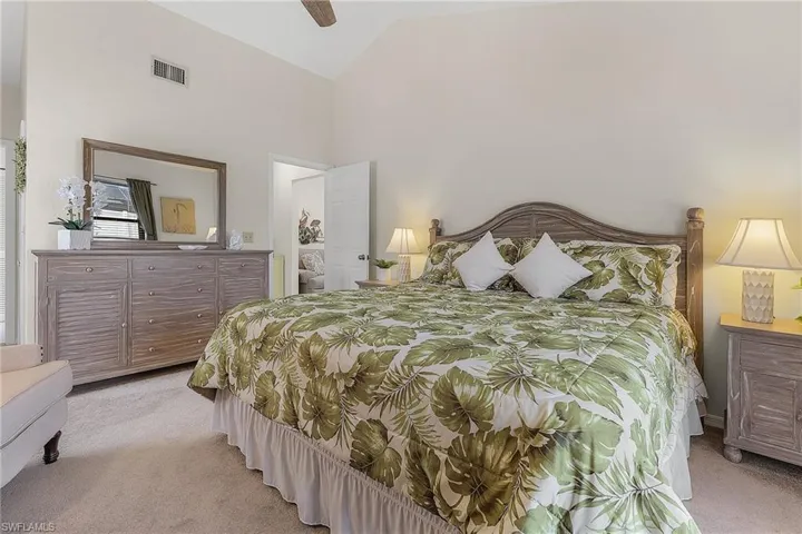 Bedroom featuring light colored carpet, vaulted ceiling, and a ceiling fan