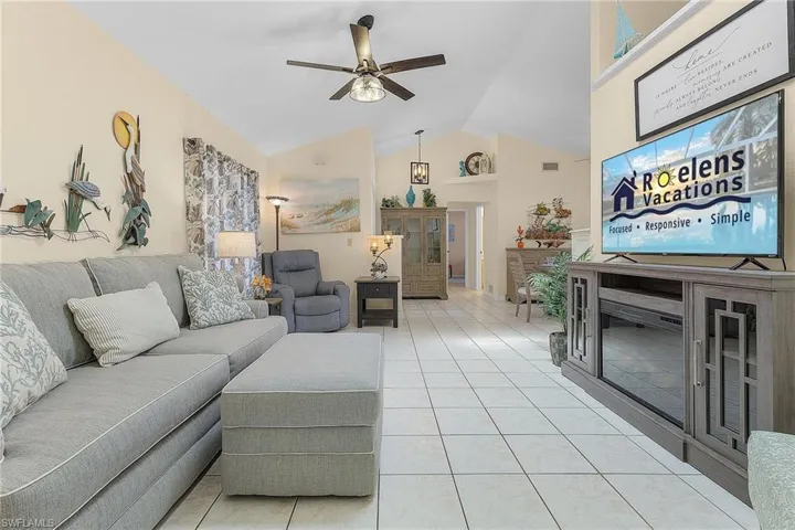 Living area with ceiling fan, lofted ceiling, and light tile patterned flooring