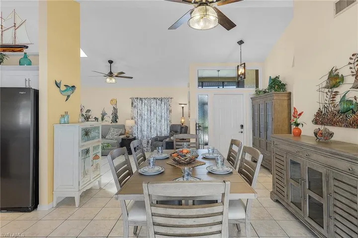 Dining area featuring a ceiling fan, lofted ceiling, and light tile patterned floors