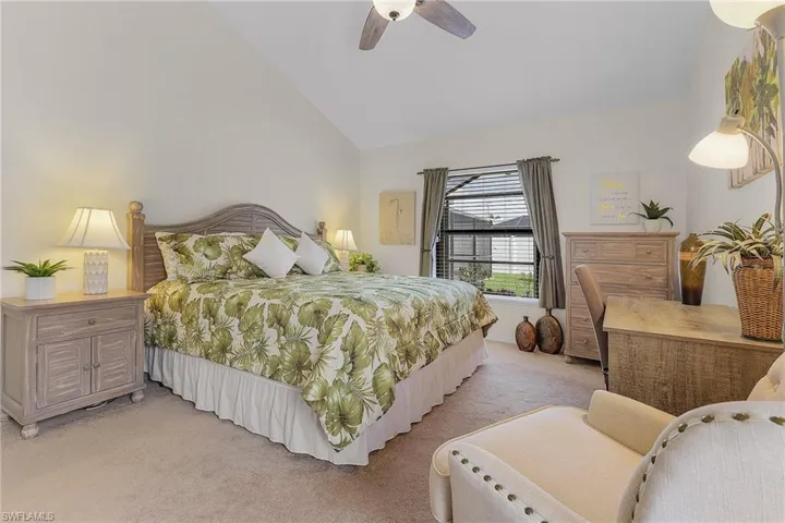 Carpeted bedroom featuring vaulted ceiling and ceiling fan