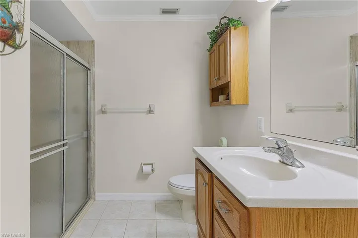 Bathroom featuring vanity, ornamental molding, light tile patterned floors, and a shower stall