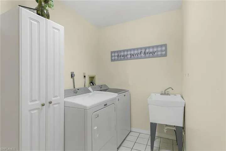 Laundry area with independent washer and dryer and light tile patterned floors