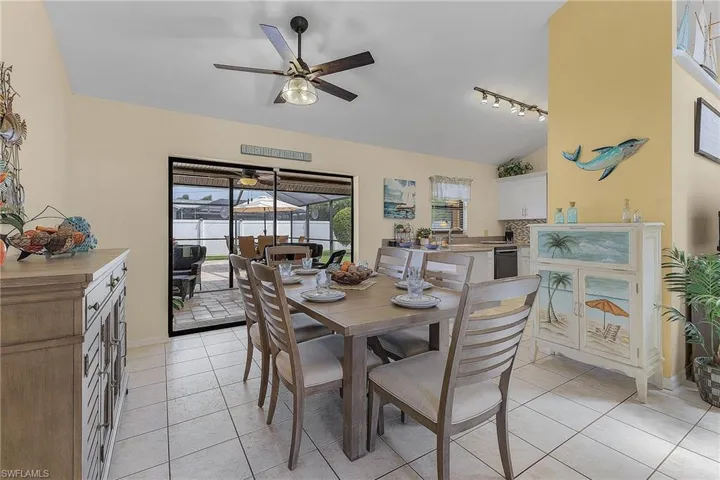Dining space with light tile patterned flooring, a ceiling fan, rail lighting, vaulted ceiling, and a sunroom