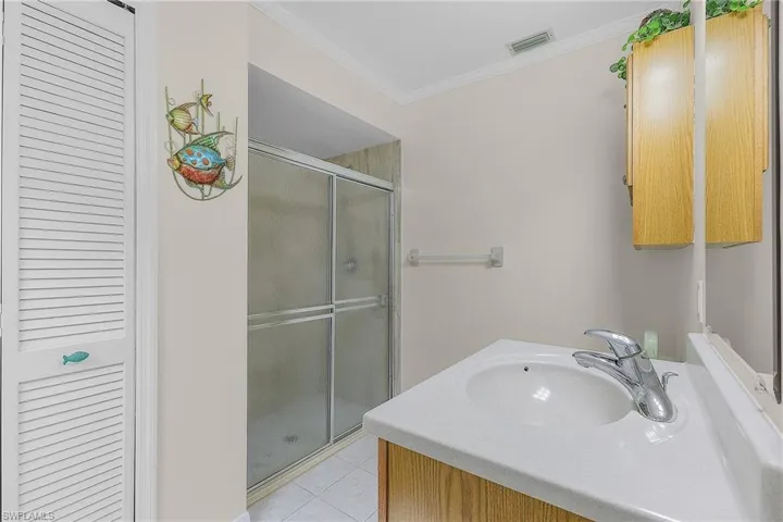 Full bath featuring vanity, crown molding, a shower stall, light tile patterned floors, and a closet