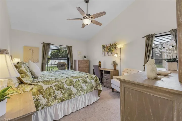 Bedroom featuring vaulted ceiling, light carpet, and ceiling fan