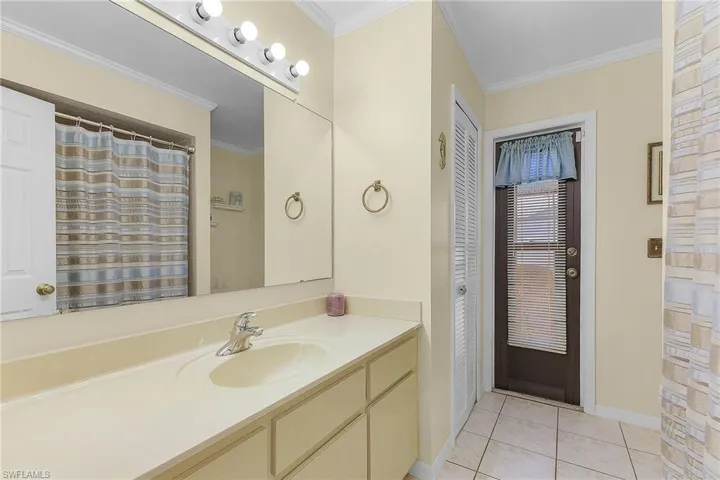 Full bath with ornamental molding, a shower with curtain, vanity, light tile patterned flooring, and a closet