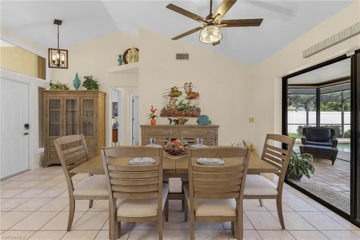 Dining area featuring light tile patterned flooring, a ceiling fan, a chandelier, and a high ceiling