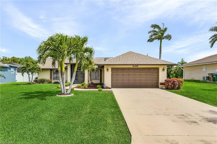Ranch-style house with a front yard, a garage, stucco siding, driveway, and roof with shingles