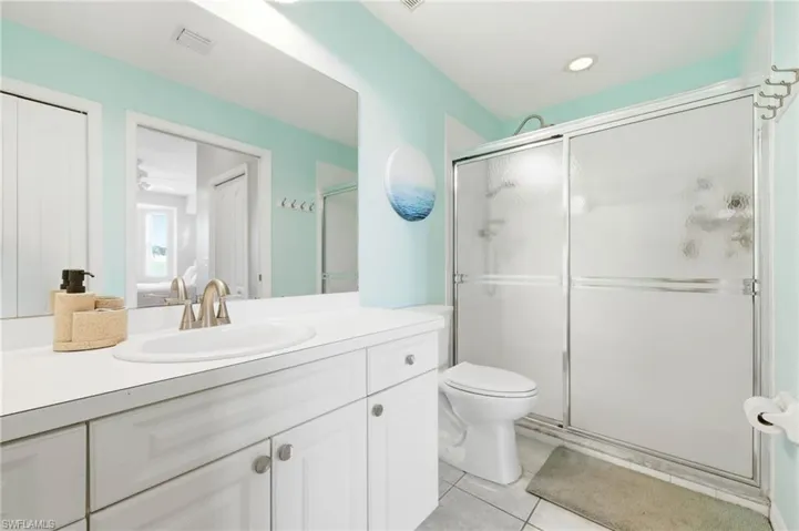 Bathroom featuring a white vanity with integrated sink, brushed nickel faucet, a large mirror, and a shower with frosted glass sliding doors